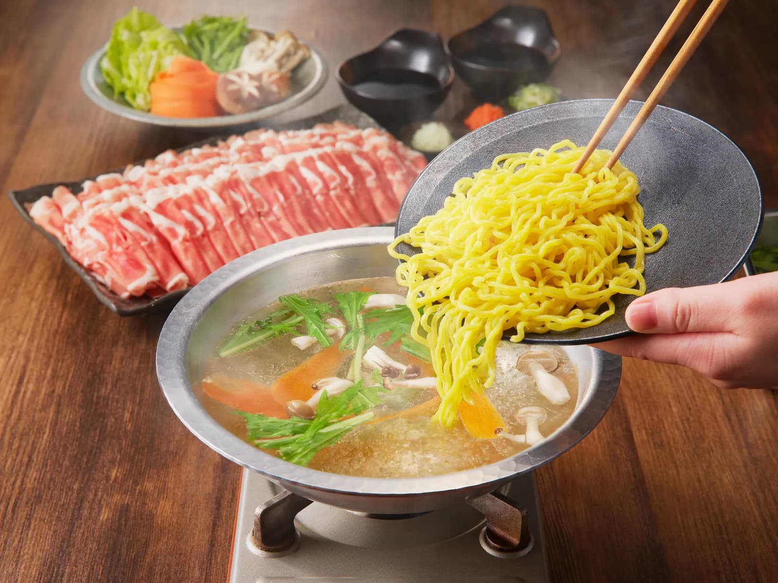 Mala broth in a round white bowl, seen straight from above: a whole red chili and a dark red jujube rest at the bottom, while split leek, coriander, white sesame and beads of chili oil float on the surface